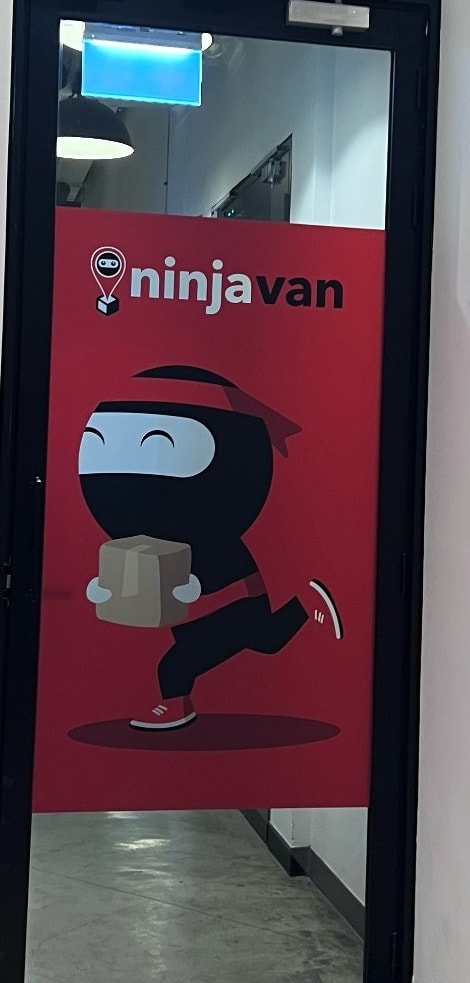 Glass office door with Ninja Van branding and mascot.